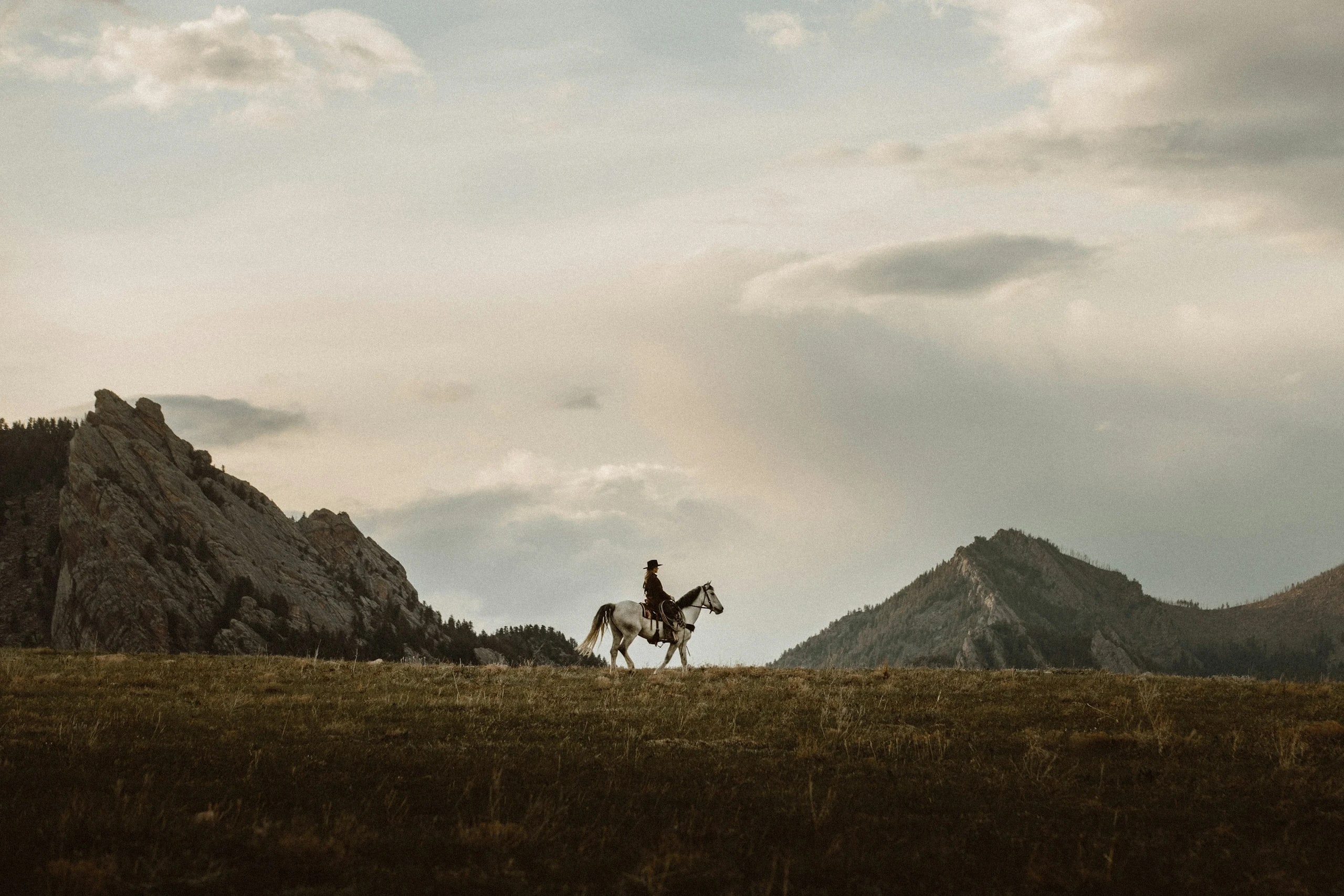 Lone rider crossing open western grassland