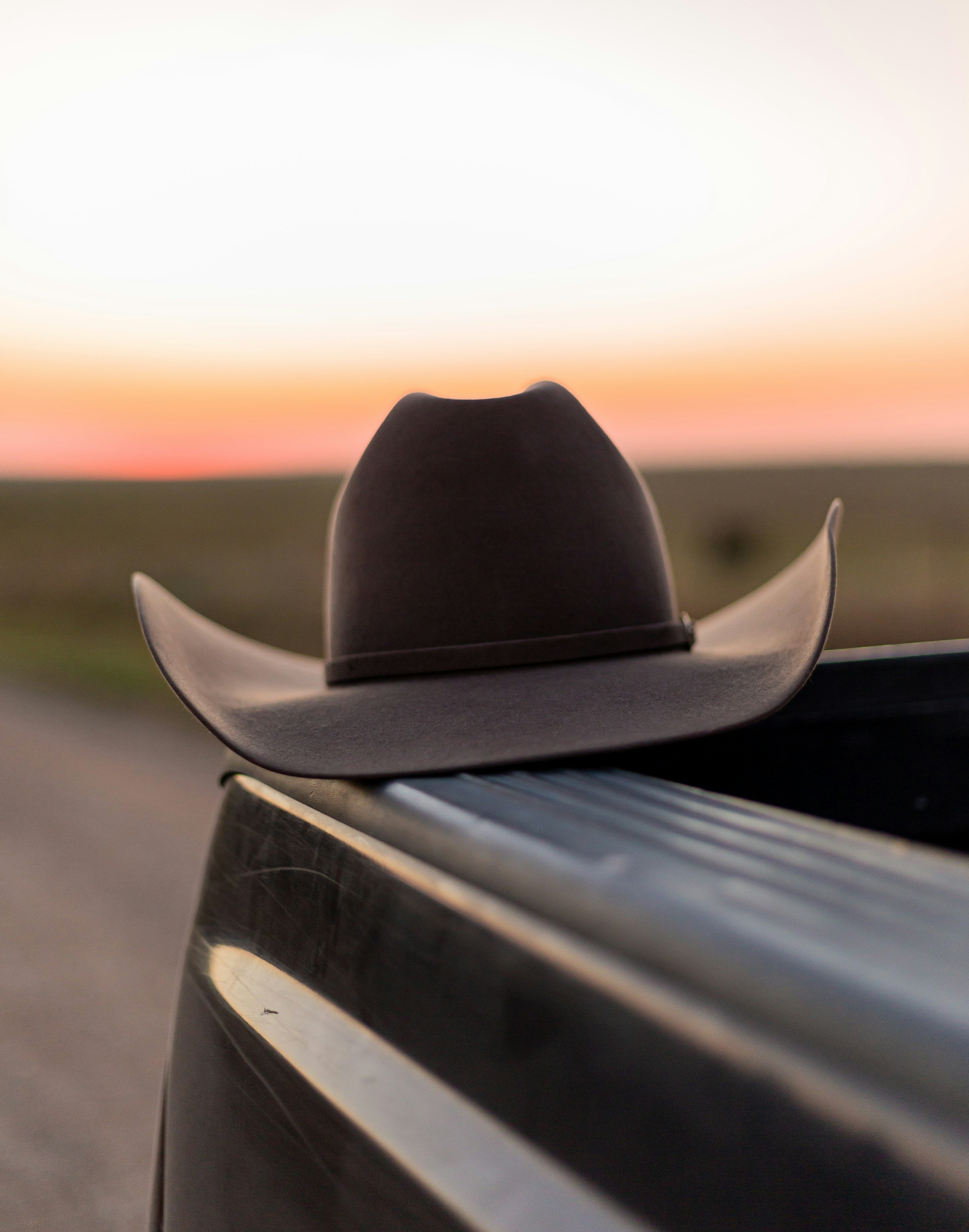 Cowboy hat resting on a truck bed at golden hour